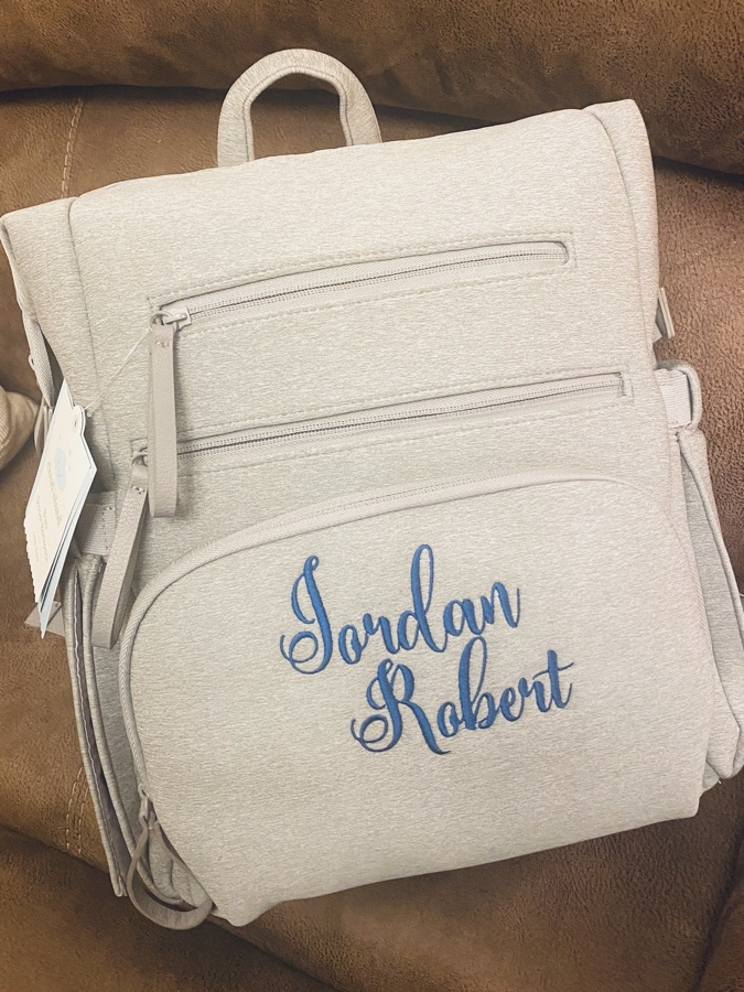Light gray backpack personalized with the name Jordan Robert in blue embroidery